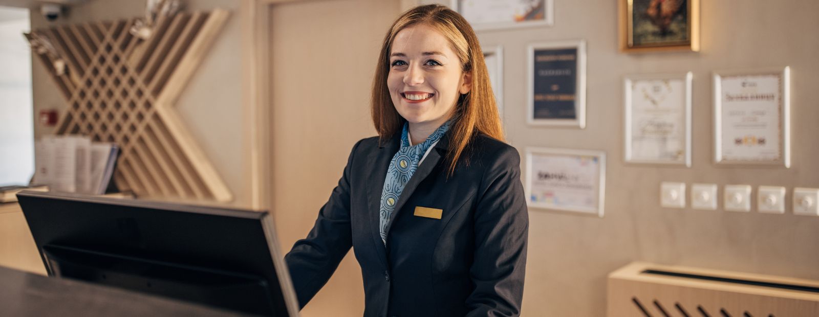 A concierge smiling at a hotel front desk.