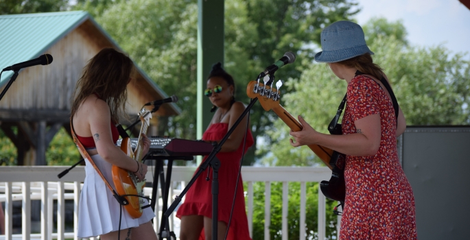 A group of musicians performing live on an outdoor stage.