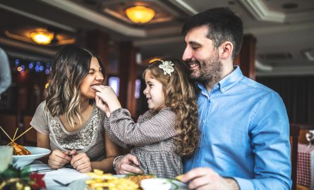 Parents and a child eating a meal in a restaurant.