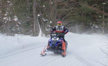 A person snowmobiling through a trail.