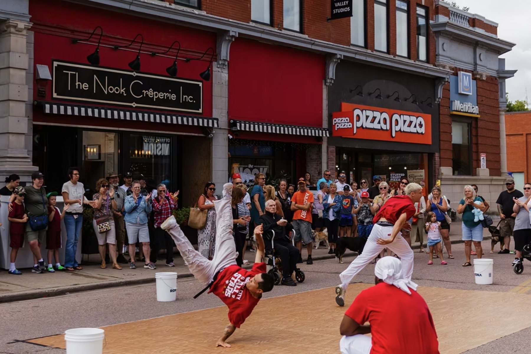 Dancers performing on a downtown street with a crowd watching.