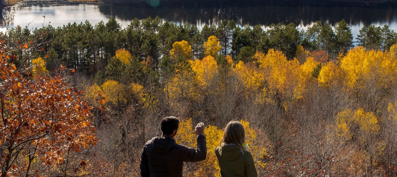 Two people hiking and overlooking a cliff.