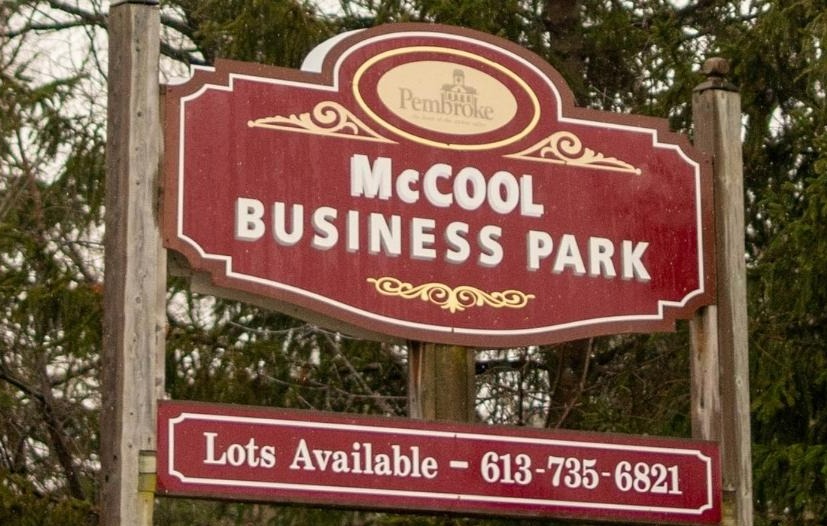 A sign for an industrial park in front of trees.