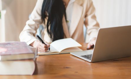 A woman taking notes at a laptop.