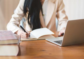 A woman taking notes at a laptop.