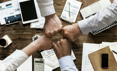 People reaching their hands to meet in the middle of the group.