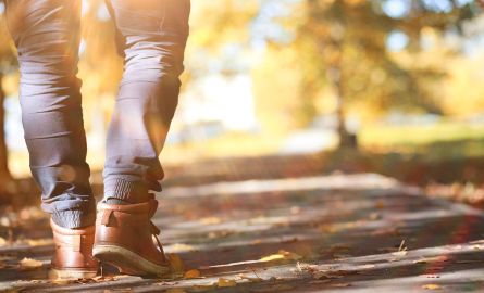 Feet walking on a treed path.