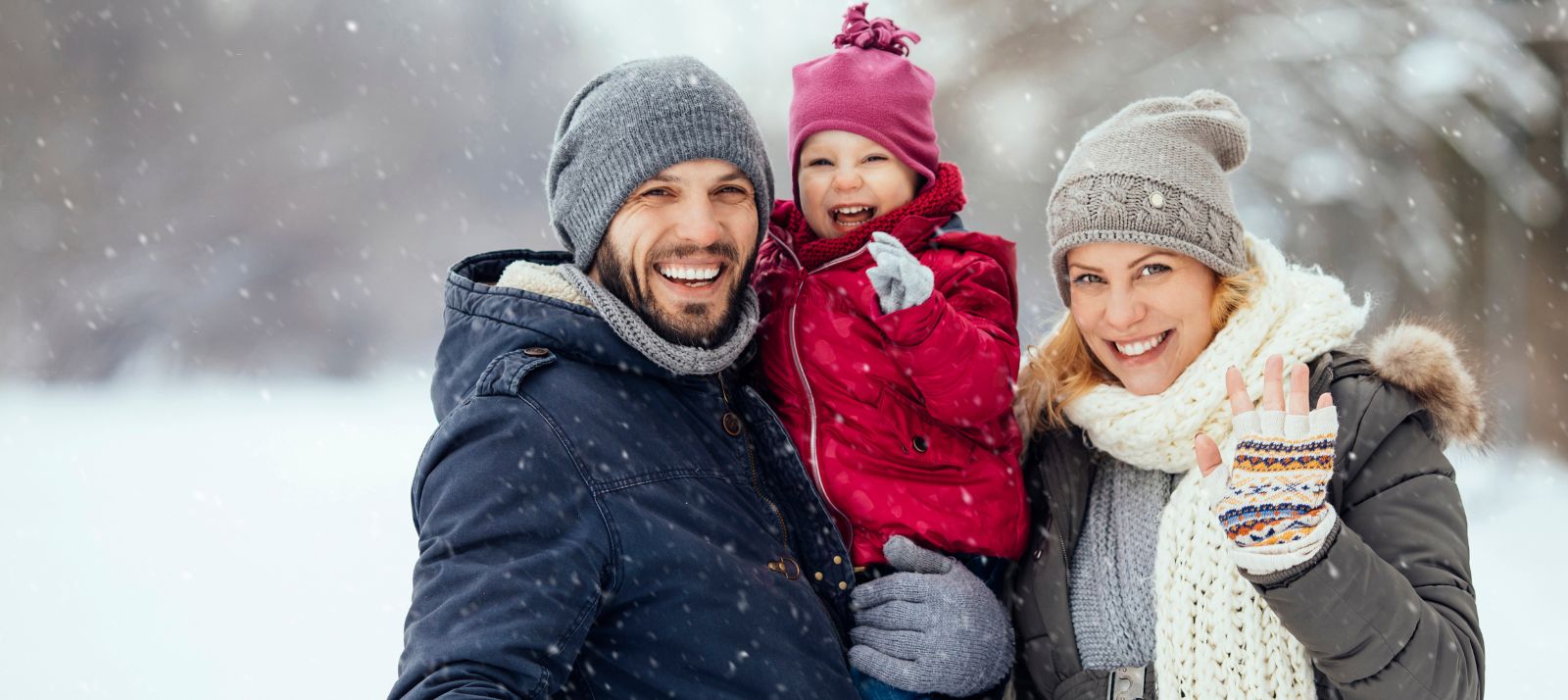 A family standing and waving in the snow.