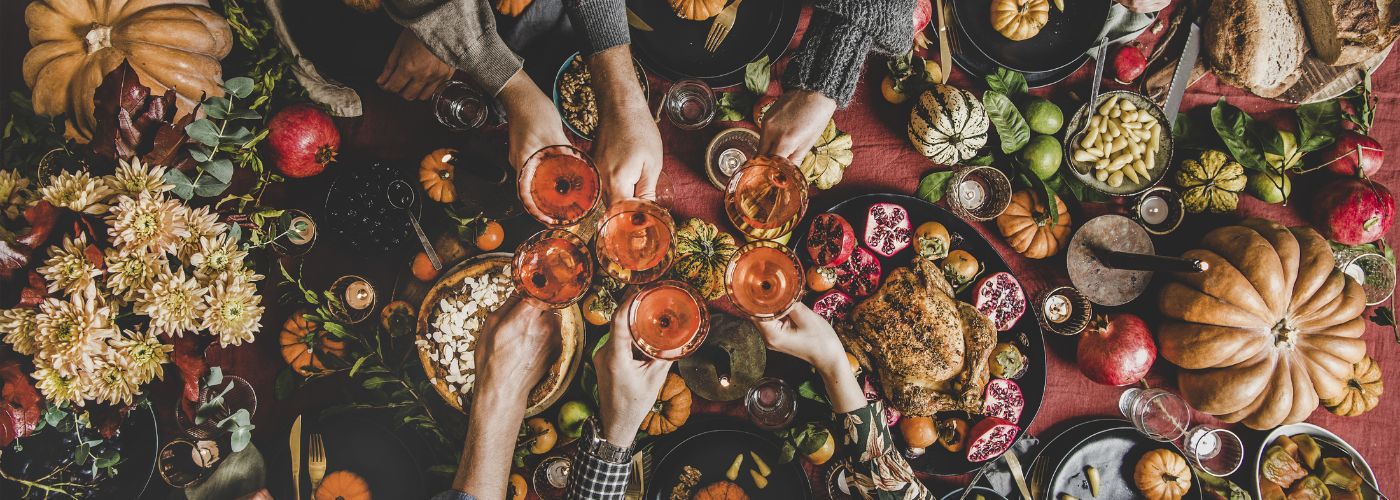 Top view of hands clinking glasses over a meal table.