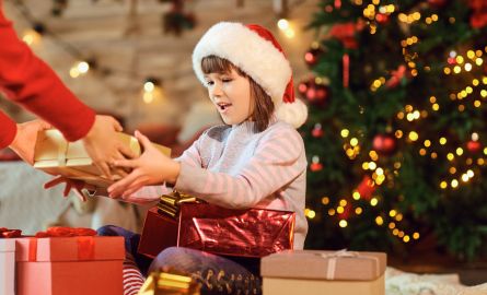 A child in a Santa hat receiving a gift.