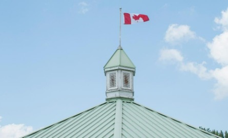 A Canada flag on top of a gazebo roof.