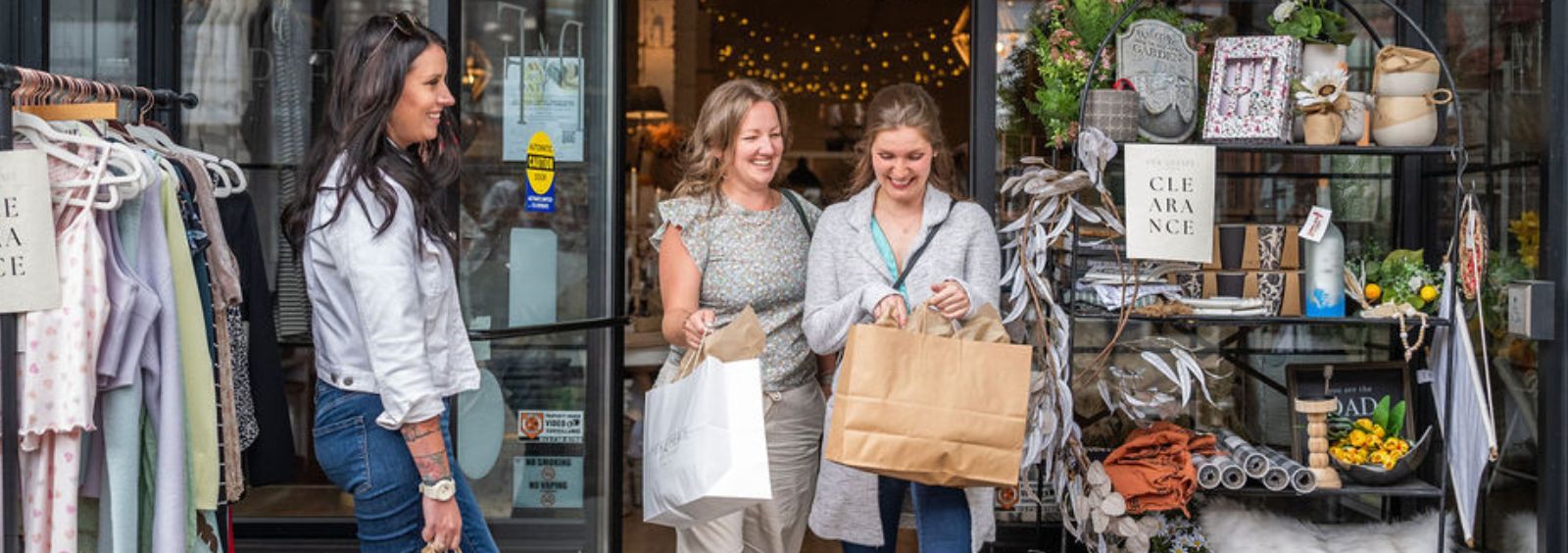 Three women exiting a small store.