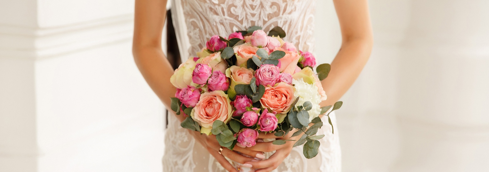 A bride holding a bouquet in front of her dress.