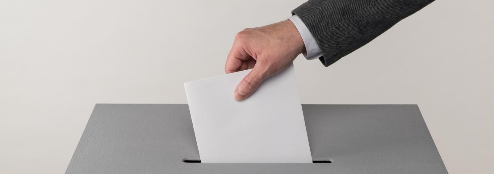 A person putting a ballot in a box.