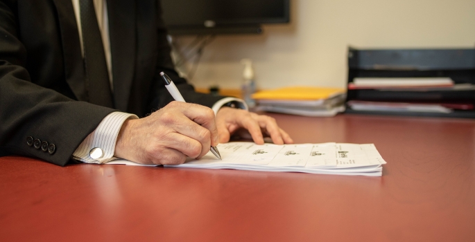 A photo of a person looking over a calendar with a phone in hand.