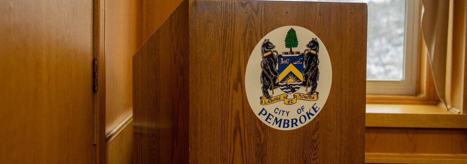 A podium with the City of Pembroke crest on it. Located within Council Chambers.