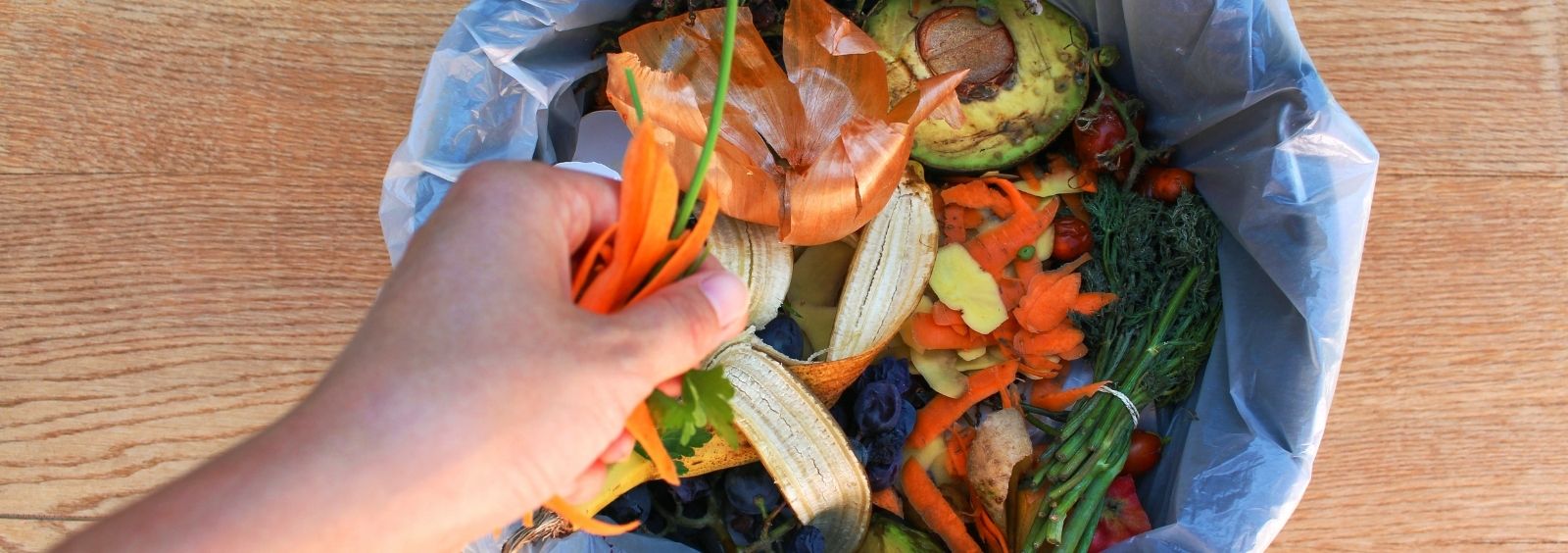 A person putting food waste in a bin.