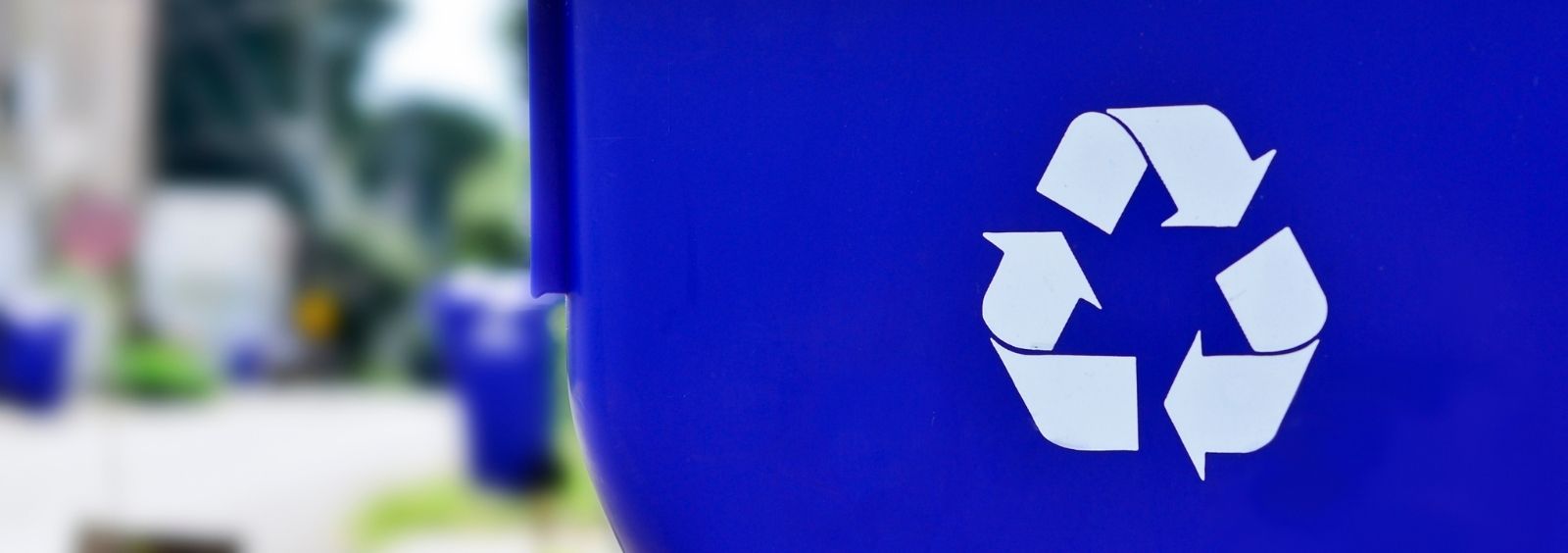 A blue recycling bin on a city street.