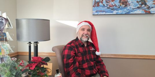 A man sitting in a chair wearing a Santa hat.