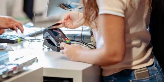 A person making a payment at a POS machine.