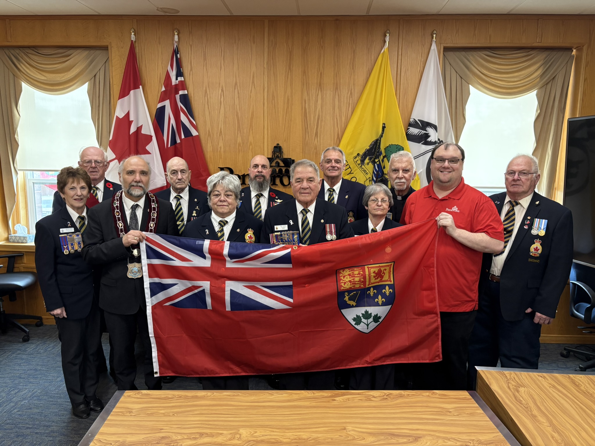 A group of veterans holding the Red Ensign flag.