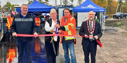 A row of people doing a ribbon cutting.