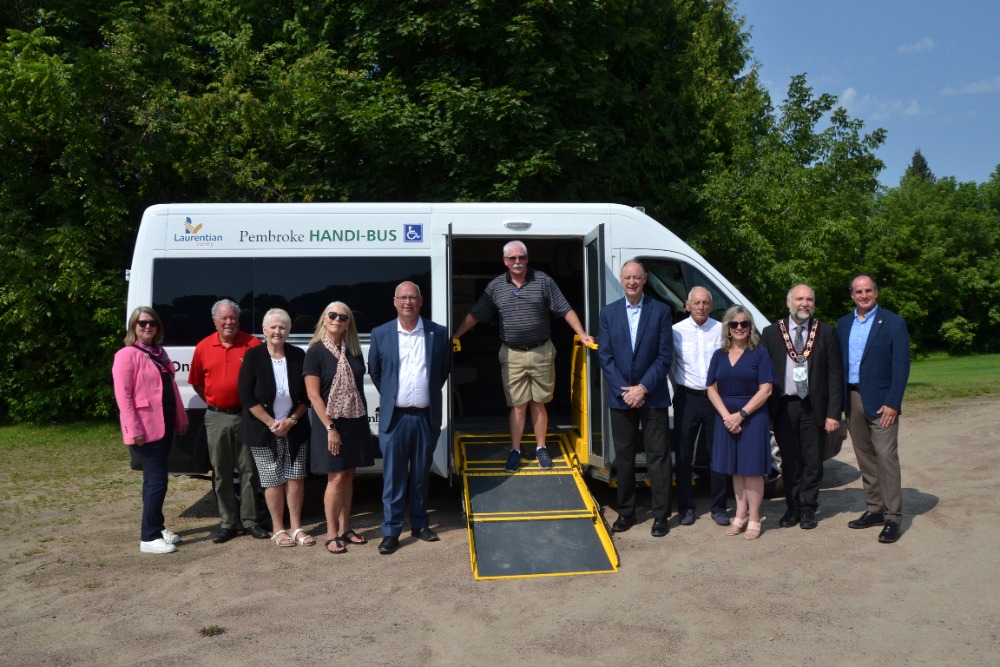 A group of people stand in front of a passenger van.