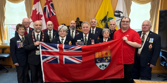 A group of veterans hold the Canadian Red Ensign flag.