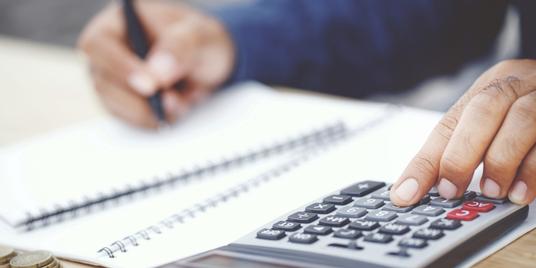 A person uses a calculator while looking over financial documents.