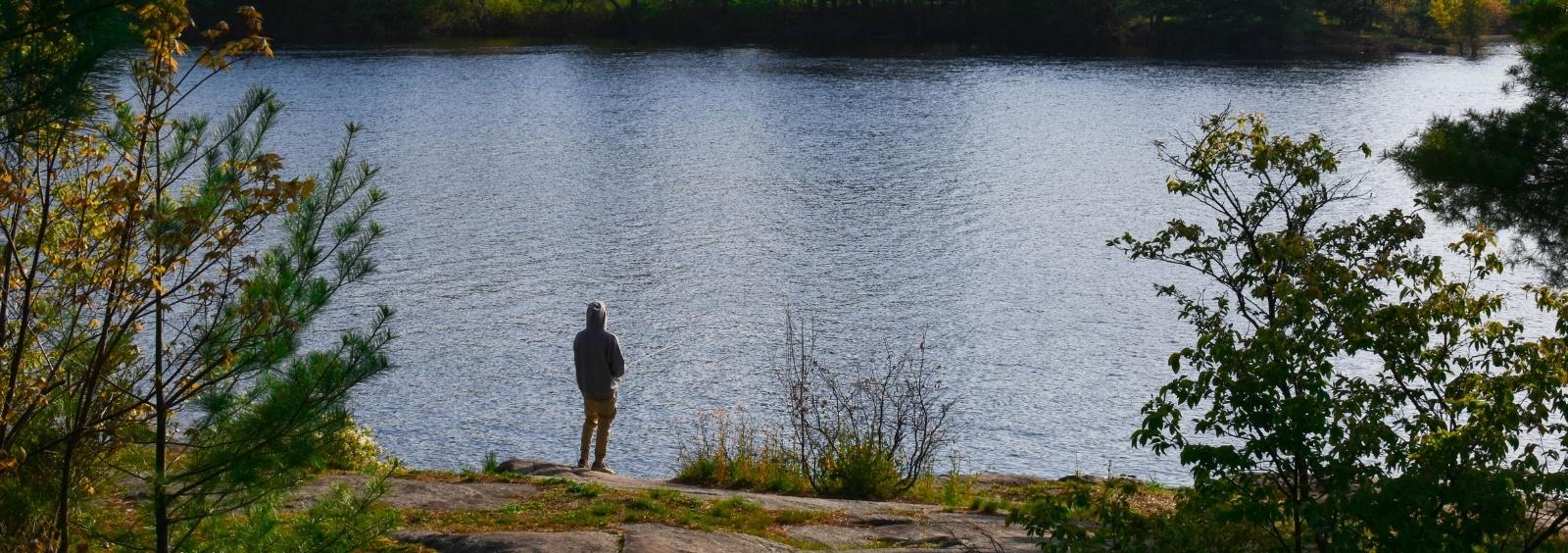 Photo from the Petawawa Point of a man fishing of a rock.