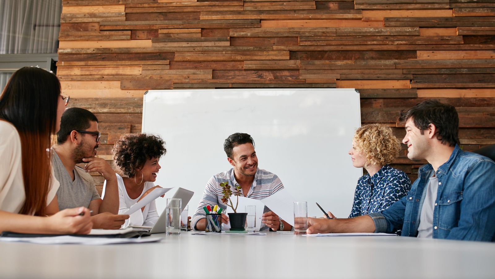 A group of people sit around a conference table discussing business.