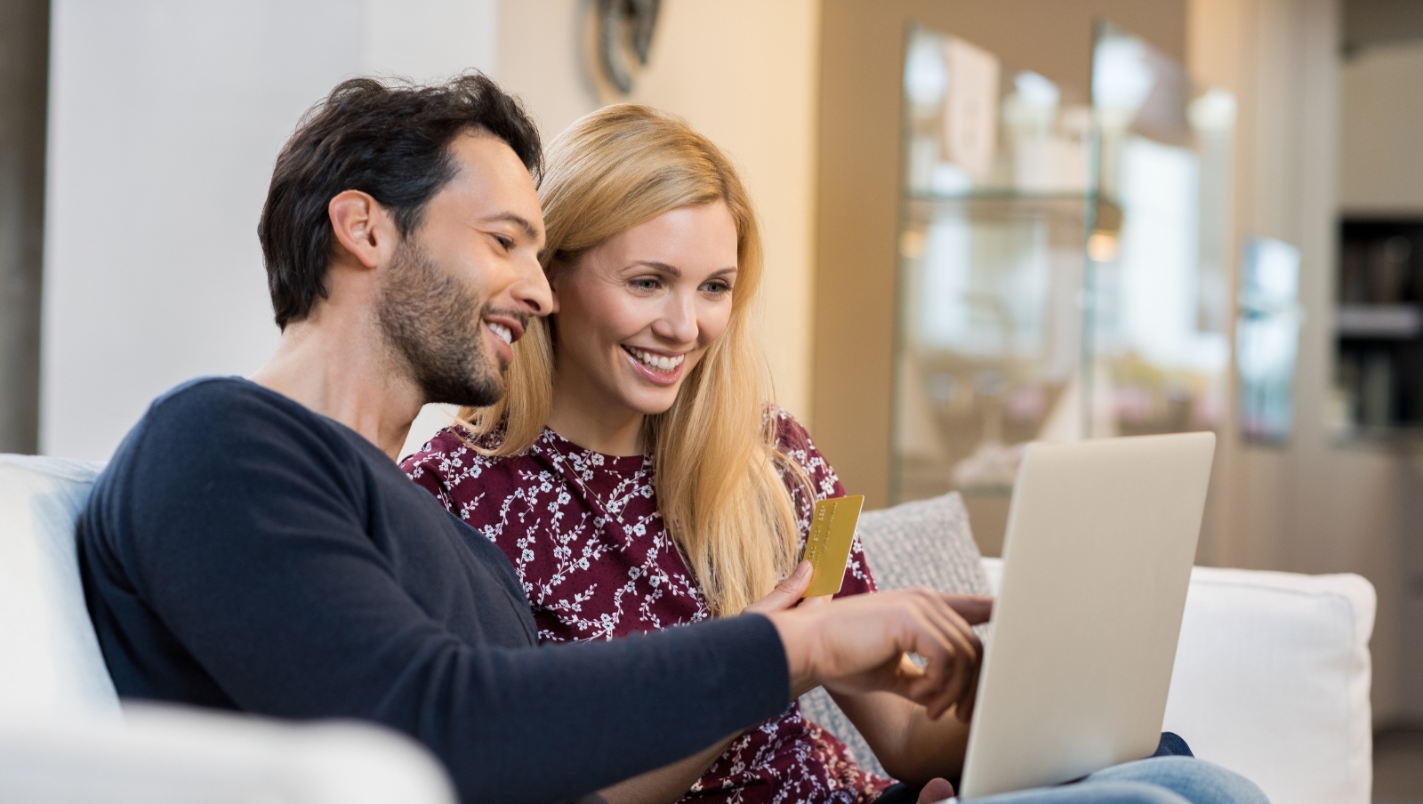 A couple smiling at a computer screen.