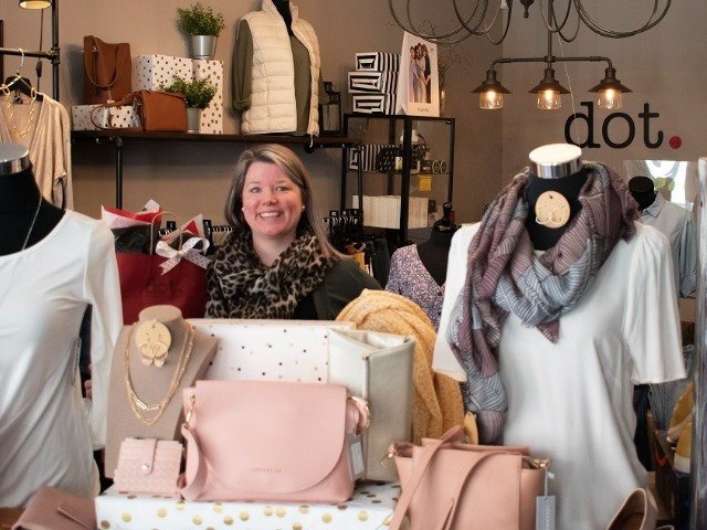 A woman stands behind items in a clothing shop