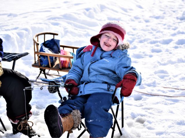 A young child laughing while ice fishing.