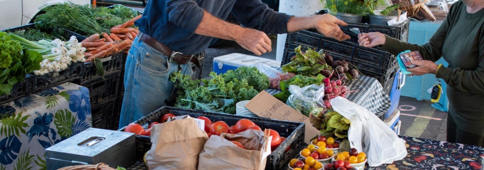 A transaction at a farmers' market vegetable stand.