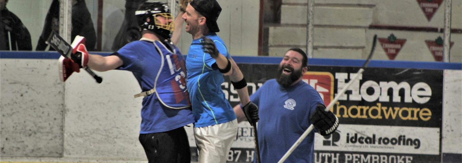 Three men celebrating in a ball hockey game.