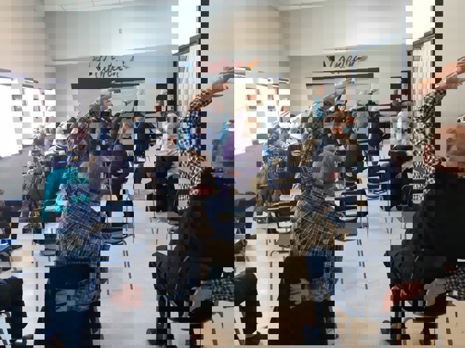 Participants sitting in chairs leaning to the side with one arm above head stretching